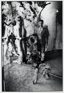 351298 Portret van ontwerper Achmed Millarson die door hem beschilderde objecten en stoffen exposeert op de tweede ...